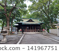 Beyond the stone lanterns and the guardian lion-dogs with red bibs, you can see the main shrine with its green copper roof and tall trees. 141967751