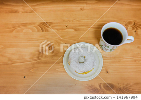 在咖啡館裡,享用一份白甜甜圈和一杯咖啡,度過一段簡單的時光。 在咖啡館裡,享用一份白甜甜圈和一杯咖啡,度過一段簡單的時光。 141967994