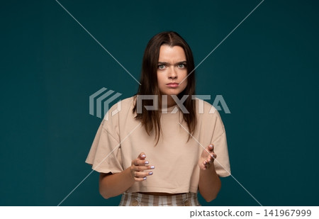 Young woman feeling frustration and confusion, raising hands while strongly expressing disagreement or questioning Young woman feeling frustration and confusion, raising hands while strongly expressing disagreement or questioning 141967999