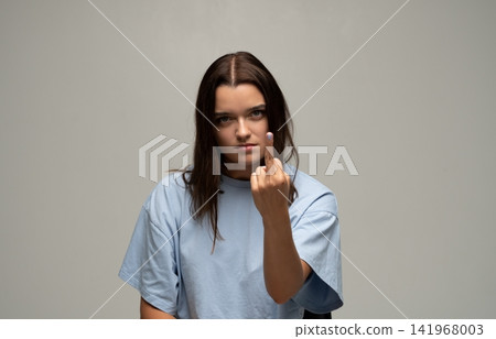 Woman expressing anger and frustration by showing a rude middle finger gesture in a studio Woman expressing anger and frustration by showing a rude middle finger gesture in a studio 141968003
