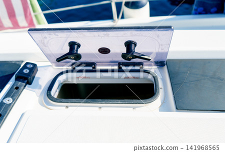 Open deck hatch on a sailing yacht with marine equipment and sea view. Concept of boating, maintenance, navigation, travel and recreation Open deck hatch on a sailing yacht with marine equipment and sea view. Concept of boating, maintenance, navigation, travel and recreation 141968565