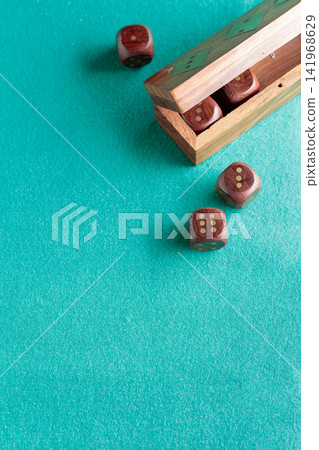 Wooden dice on a green cloth. Wooden dice on a green cloth. 141968629