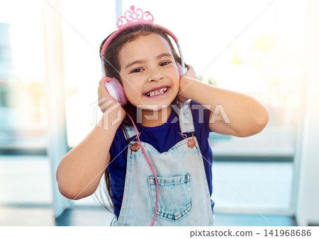 Young child, headphones and portrait for music listening in house with streaming song, radio sound and girl podcast. Happy, kid and earphones for media with smile, fun audio and playlist by window Young child, headphones and portrait for music listening in house with streaming song, radio sound and girl podcast. Happy, kid and earphones for media with smile, fun audio and playlist by window 141968686