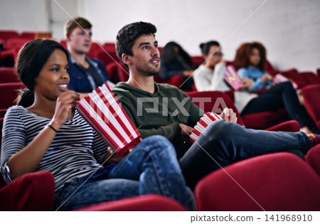 Movie, date and couple in cinema at night with popcorn to relax and watch in theatre with happiness. Film, experience and people in audience enjoy funny comedy, drama performance or eating snack food Movie, date and couple in cinema at night with popcorn to relax and watch in theatre with happiness. Film, experience and people in audience enjoy funny comedy, drama performance or eating snack food 141968910