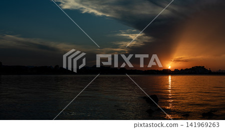 Panoramic sunset view of the solar eclipse over the sea and Denia coastline with dark clouds and golden light Panoramic sunset view of the solar eclipse over the sea and Denia coastline with dark clouds and golden light 141969263
