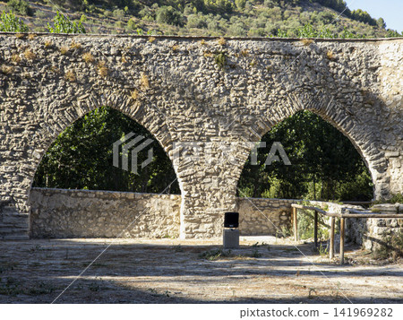 Two stone arches of ancient aqueduct surrounded by trees in a natural setting Two stone arches of ancient aqueduct surrounded by trees in a natural setting 141969282