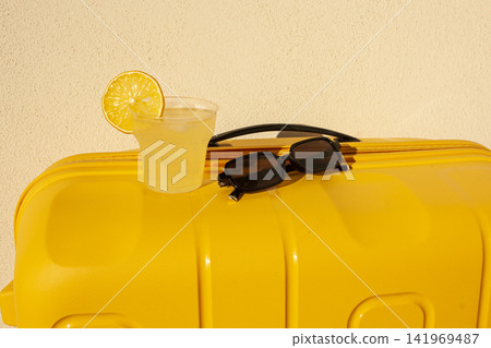 Lemonade, yellow suitcase, sunglasses, cocktail, juice, summer background Lemonade, yellow suitcase, sunglasses, cocktail, juice, summer background 141969487