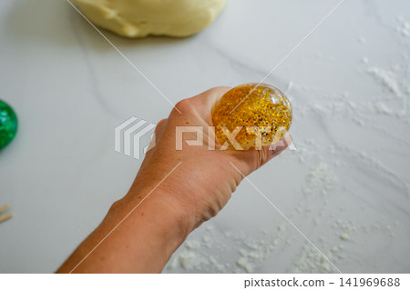 Hand Squeezing Gold Glitter Squishy Toy Stress Relief Concept Hand Squeezing Gold Glitter Squishy Toy Stress Relief Concept 141969688