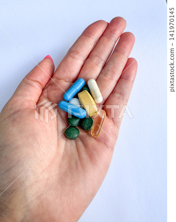 Assorted vitamins and supplements in a female hand, colorful capsules and tablets for health, pharmacy and wellness themes Assorted vitamins and supplements in a female hand, colorful capsules and tablets for health, pharmacy and wellness themes 141970145