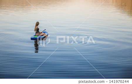 Woman on Paddleboard Enjoying Quiet Reflection Woman on Paddleboard Enjoying Quiet Reflection 141970244