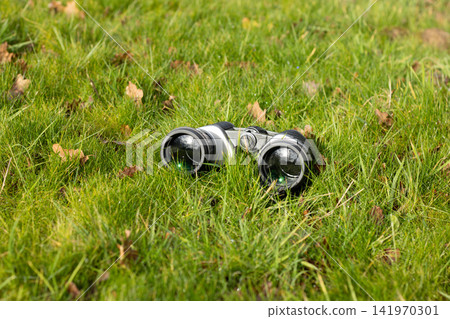 Black binoculars on a fallen tree, travel concept Black binoculars on a fallen tree, travel concept 141970301