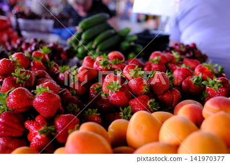 Fresh fruits and vegetables displayed at local farmers market with ripe apricots, strawberries and cucumbers, colorful seasonal produce for healthy shopping and natural nutrition 141970377