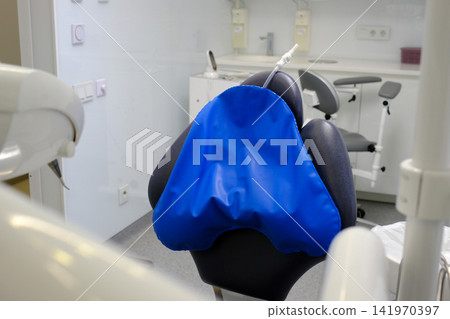 Blue ergonomic dental headrest pillow placed on dental chair providing comfortable patient support during treatment in modern dental clinic close up medical equipment Blue ergonomic dental headrest pillow placed on dental chair providing comfortable patient support during treatment in modern dental clinic close up medical equipment 141970397
