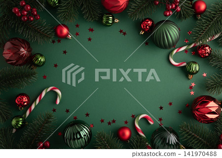 Festive Christmas border with ornaments pine branches and candy canes on dark green background Festive Christmas border with ornaments pine branches and candy canes on dark green background 141970488