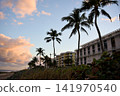 Palm Trees Silhouetted Against A Hotel Building At Sunset 141970540