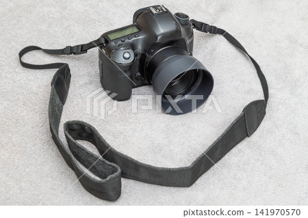 Digital SLR Camera with Lens and Strap on Textured Surface Digital SLR Camera with Lens and Strap on Textured Surface 141970570