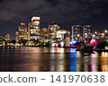 Coastal City Buildings Glow Above Calm Nighttime Water 141970638