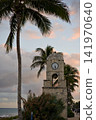 Stone Clock Tower Framed By Palm Trees Near The Ocean 141970640