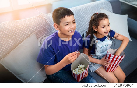 Children, popcorn and television or excited on couch in home for movie entertainment, siblings or subscription. Boy, girl and sofa in apartment with snacks together in living room, streaming or film Children, popcorn and television or excited on couch in home for movie entertainment, siblings or subscription. Boy, girl and sofa in apartment with snacks together in living room, streaming or film 141970904