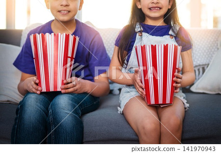 Kids, popcorn and sofa to watch, cartoon and movie with food, growth and development of siblings. Children, boy and girl in living room, couch and eating for film, house and waiting for start Kids, popcorn and sofa to watch, cartoon and movie with food, growth and development of siblings. Children, boy and girl in living room, couch and eating for film, house and waiting for start 141970943