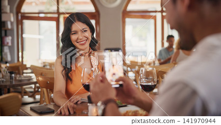 Phone, picture and couple in restaurant for date, social media and memory for romantic dinner. Fine dining, happy and man with photo of woman for bonding, moment and post for anniversary celebration Phone, picture and couple in restaurant for date, social media and memory for romantic dinner. Fine dining, happy and man with photo of woman for bonding, moment and post for anniversary celebration 141970944