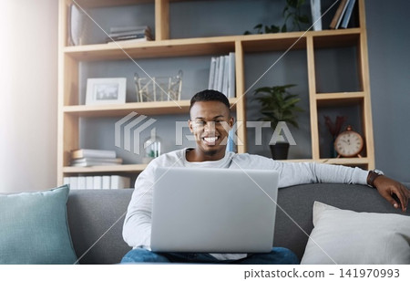 Man, portrait and laptop in home on sofa, networking and social media for online streaming in living room. Happy, research and technology on website, remote work and internet blog in apartment 141970993