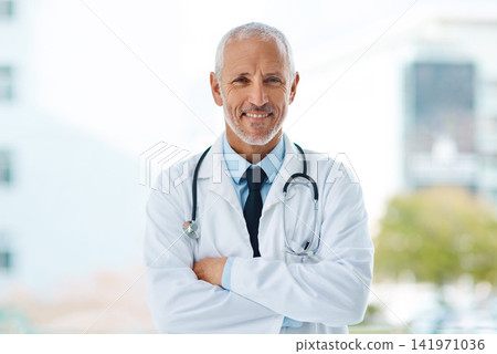 Doctor, happy and portrait of mature man in a hospital at a cardiology clinic with arms crossed. Professional, medical employee and stethoscope with healthcare, surgeon and cardiologist consultant 141971036