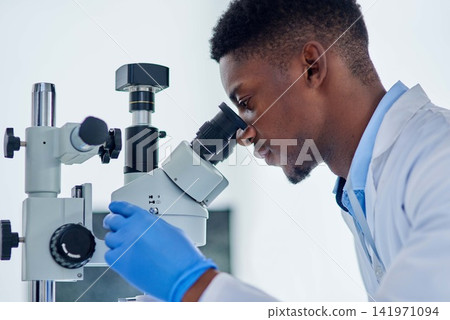 Science, research and black man with microscope for analysis, investigation or medical engineering in laboratory. Biotech, lab technician or scientist checking vaccine sample for pharmaceutical test. Science, research and black man with microscope for analysis, investigation or medical engineering in laboratory. Biotech, lab technician or scientist checking vaccine sample for pharmaceutical test. 141971094