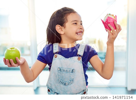 Smile, choice and girl with fruit, dessert and eating of healthy, food and growth of development of child. Kitchen, decision and kid with apple, cupcake and thinking of nutrition or cake in house Smile, choice and girl with fruit, dessert and eating of healthy, food and growth of development of child. Kitchen, decision and kid with apple, cupcake and thinking of nutrition or cake in house 141971154