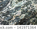 Close up of textured rock surface with colorful mineral patterns and details 141971364
