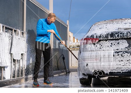 Concept of vehicle maintenance, car care, cleanliness transportation and modern automated washing services. Man Washing Car at Self Service Car Wash Using Foam Cleaning Concept of vehicle maintenance, car care, cleanliness transportation and modern automated washing services. Man Washing Car at Self Service Car Wash Using Foam Cleaning 141971409