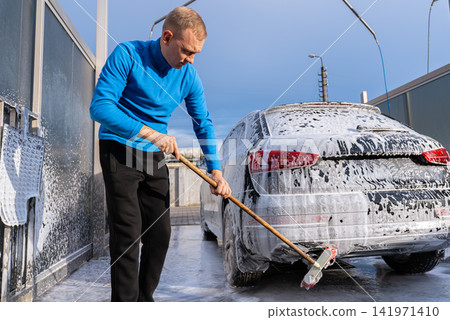 Concept of vehicle maintenance, car care, cleanliness transportation and modern automated washing services. Man Washing Car at Self Service Car Wash Using Foam Cleaning Concept of vehicle maintenance, car care, cleanliness transportation and modern automated washing services. Man Washing Car at Self Service Car Wash Using Foam Cleaning 141971410
