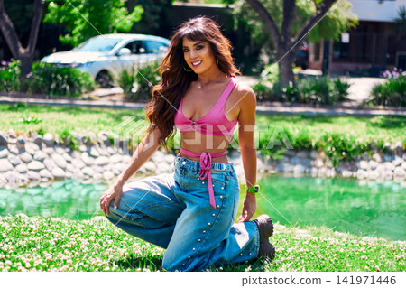 Beautiful mature Latina Arab brunette dancing in an outdoor park. Wearing retro pink clothing and jeans, with makeup, she dances with style, attitude, beauty, and freedom. Beautiful mature Latina Arab brunette dancing in an outdoor park. Wearing retro pink clothing and jeans, with makeup, she dances with style, attitude, beauty, and freedom. 141971446