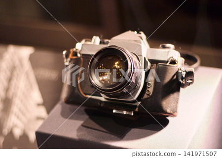Antique camera, displayed for appreciation, next to a light from above, journalistic camera with its case in good condition, antique, journalism, analog photography. Antique camera, displayed for appreciation, next to a light from above, journalistic camera with its case in good condition, antique, journalism, analog photography. 141971507
