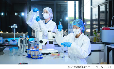 Two Scientists in Protective Gear Conducting Research Experiments in Modern Laboratory 141972275
