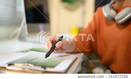 Graphic Designer Reviewing Color Swatches with Stylus Pen at Creative Workspace 141972588