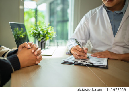 Psychiatrist Writing Notes on Clipboard During Patient Consultation in Medical Office Psychiatrist Writing Notes on Clipboard During Patient Consultation in Medical Office 141972639