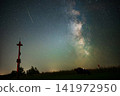 Milky Way and Meteor Shower over Wooden Wayside Cross and People Relaxing under Starry Night Sky 141972950