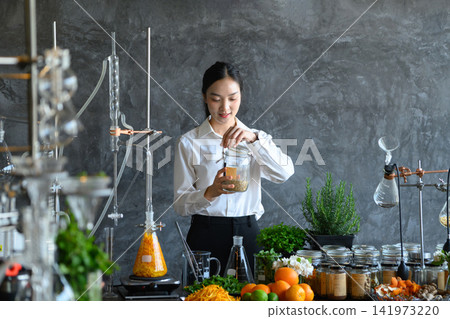 Young Asian Woman Scientist Researching Natural Herbal Extracts in Modern Laboratory with Botanical Ingredients Young Asian Woman Scientist Researching Natural Herbal Extracts in Modern Laboratory with Botanical Ingredients 141973220
