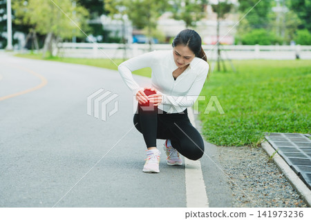 Asian Woman Runner Suffering Knee Pain Injury During Outdoor Workout in Park Asian Woman Runner Suffering Knee Pain Injury During Outdoor Workout in Park 141973236