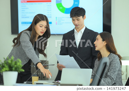 Professionals reviewing digital charts and printed reports during strategy meeting at desk Professionals reviewing digital charts and printed reports during strategy meeting at desk 141973247