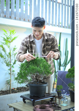 A man making bonsai pruning with precision care and craftsmanship A man making bonsai pruning with precision care and craftsmanship 141973380