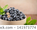 Fresh ripe blueberries with mint leaves in ceramic bowl 141973774