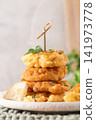 Golden Crispy Cod Fritters Stacked on Rustic Plate 141973778