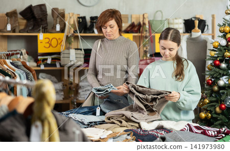 Mother with her teenage daughter choose trousers together in fashionable clothing store Mother with her teenage daughter choose trousers together in fashionable clothing store 141973980