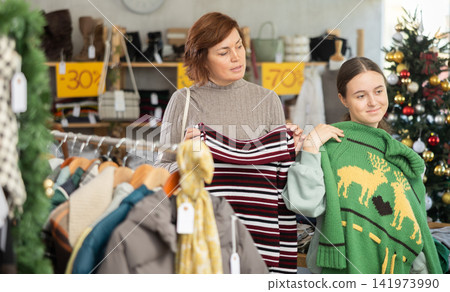 Adult woman and teenage girl choose sweater 141973990