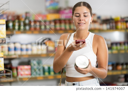 Girl in supermarket scan QR code on jar canned food Girl in supermarket scan QR code on jar canned food 141974007