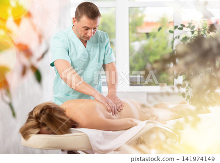 the client lies while the man gives a massage the client lies while the man gives a massage 141974149