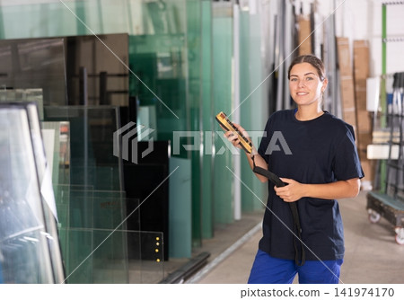 Female worker using control panel and lifting mechanism controls movement of window panes in an industrial workshop Female worker using control panel and lifting mechanism controls movement of window panes in an industrial workshop 141974170