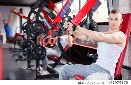 Young man trains his arms on machine 141974176